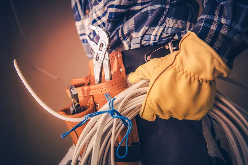 hip view of electrician wearing gloves holding a length of rounded up wire